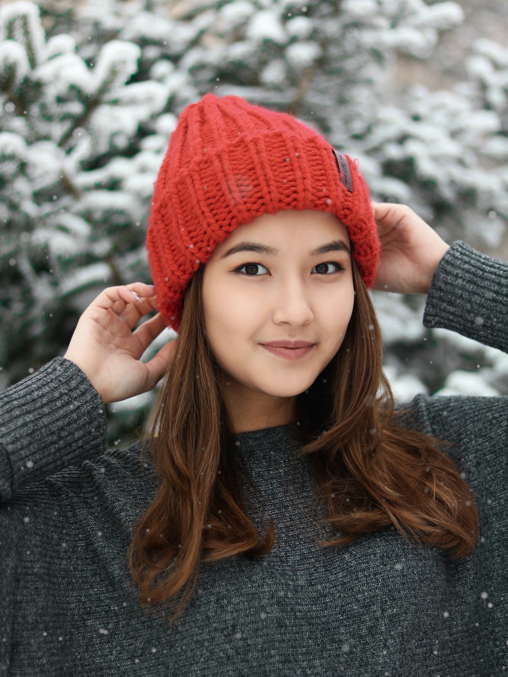 woman in grey knit sweater and red knit cap