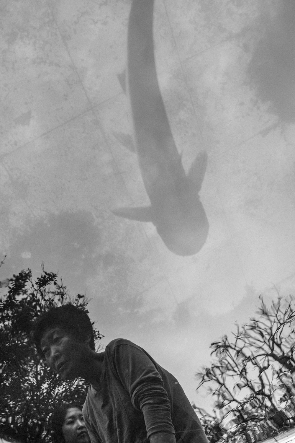 grayscale photography of two women standing near trees