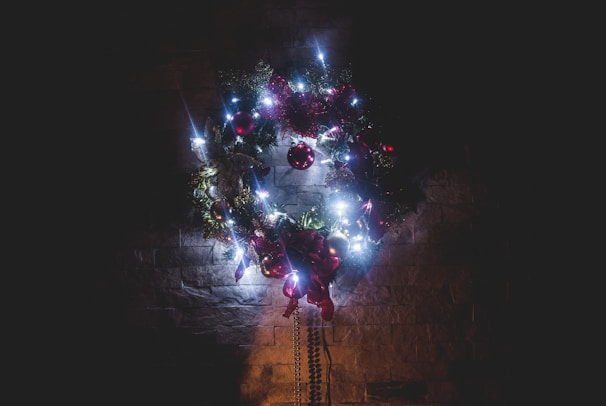 Classic retro holiday wreath hanging on a warmly lit front door, surrounded by soft glowing string lights.
