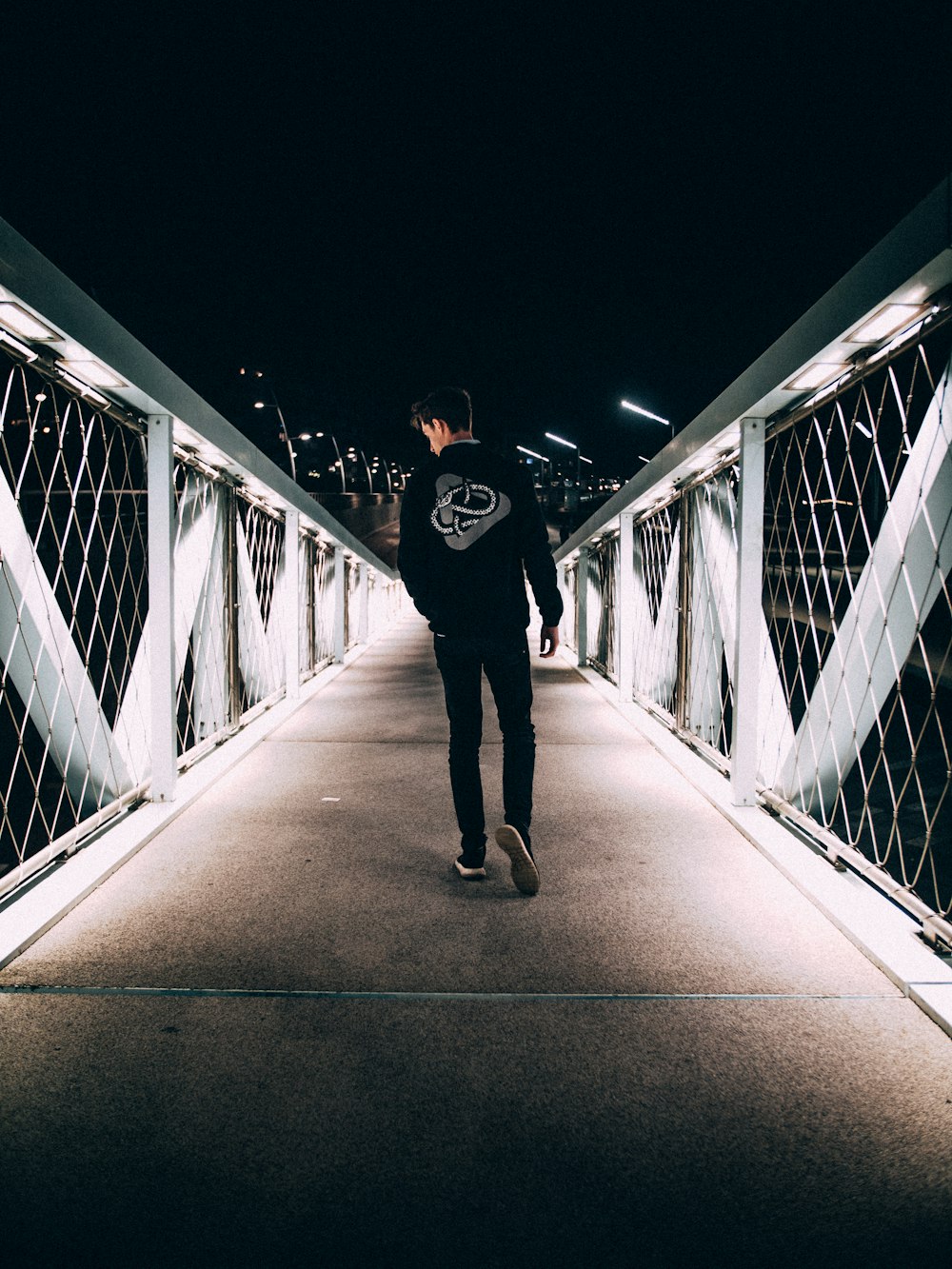 man walking on concrete bridge during nighttime