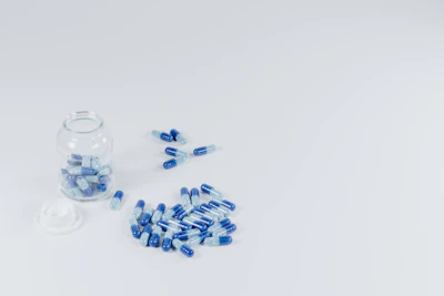 Close-up of natural supplements capsules spilling from a glass jar onto a rustic table.