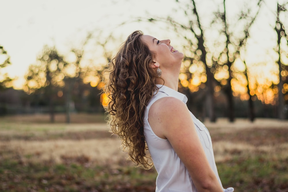 shallow focus photo of woman smiling in white sleeveless shirt