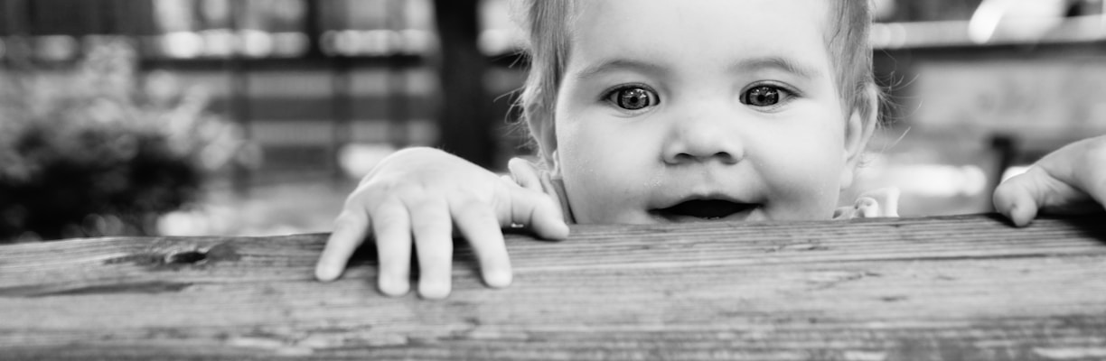 greyscale photo of baby on wooden bench