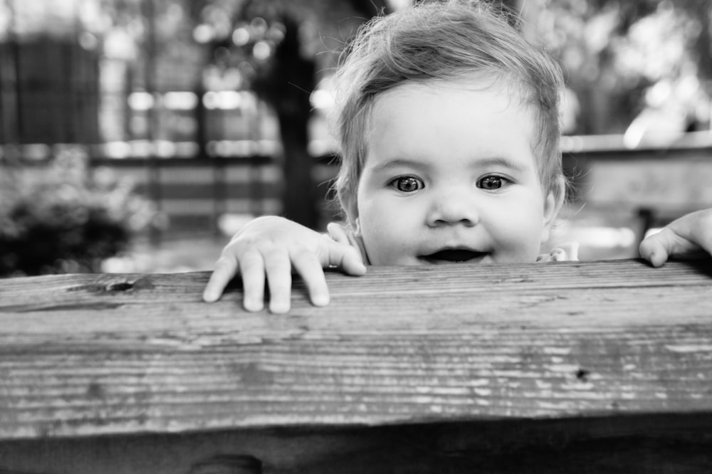 greyscale photo of baby on wooden bench
