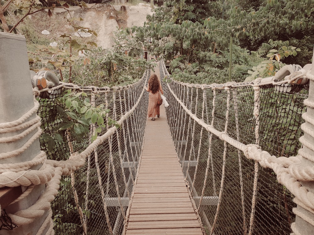Mujer en vestido largo caminando en puente colgante