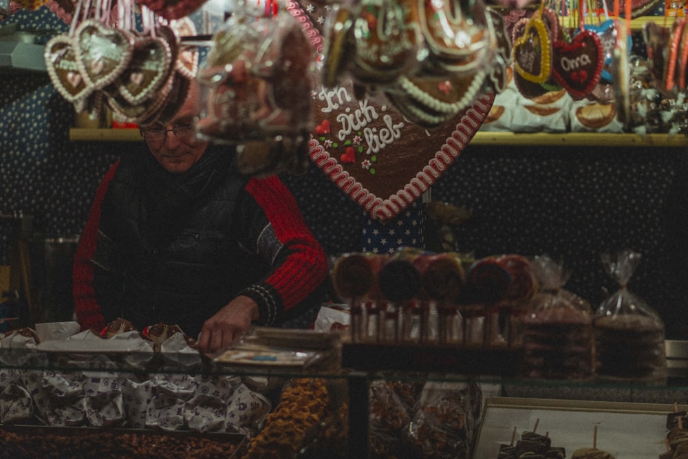 man wearing black and red jacket picking up sweets