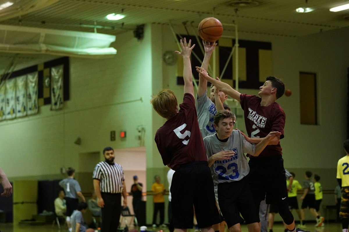 A coach demonstrates a basketball drill to youth players on an indoor court during practice.