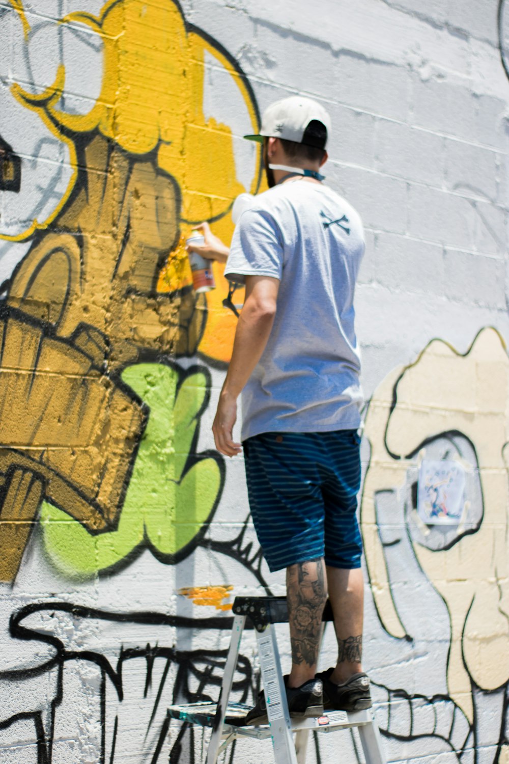 man paint spraying wall during daytime