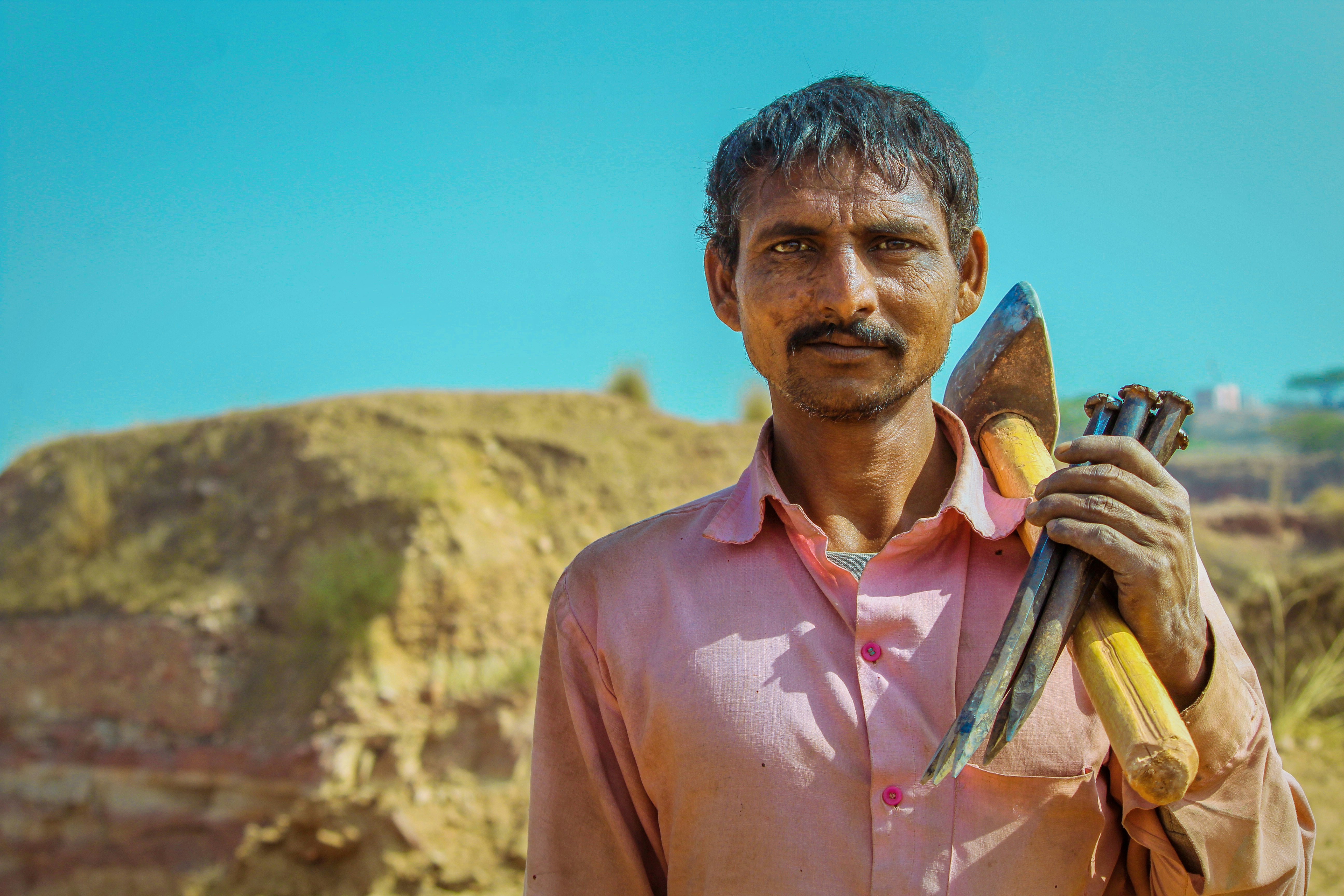 man in red button-up dress shirt carrying tools