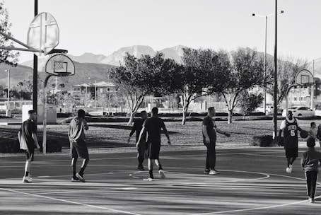 A diverse group of people playing wheelchair basketball outdoors, smiling and engaged.