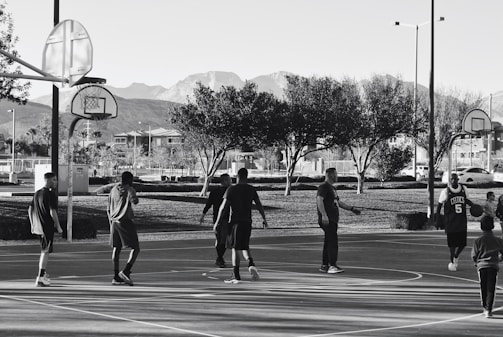 A diverse group of people playing wheelchair basketball outdoors.