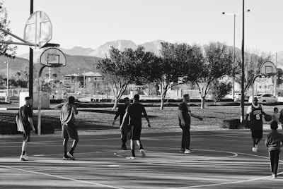 A group of kids playing basketball outdoors, smiling and cheering each other on.