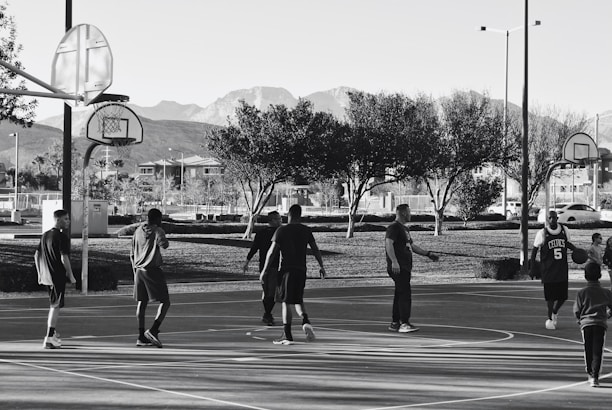 A diverse group of people playing basketball together outdoors, smiling and supporting each other.