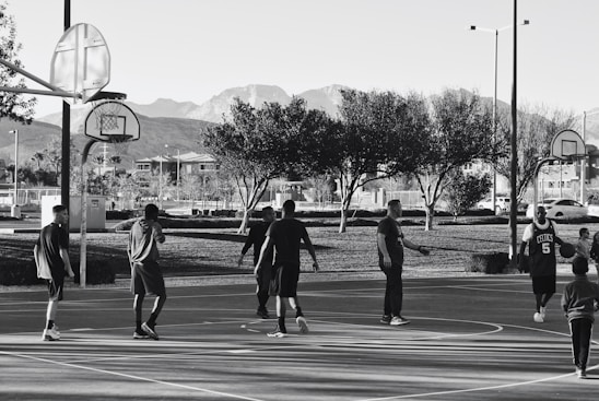 A diverse group of players enjoying a basketball game on an outdoor court.