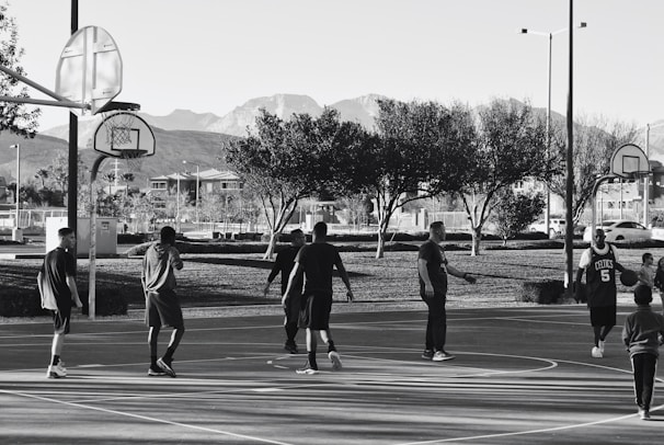 A group of diverse children laughing and playing basketball on an outdoor court.