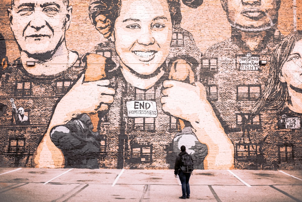 man standing facing murals