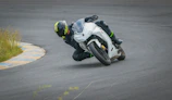 A rider in black and magenta gear leaning into a curve on a closed course, showcasing skill and safety.