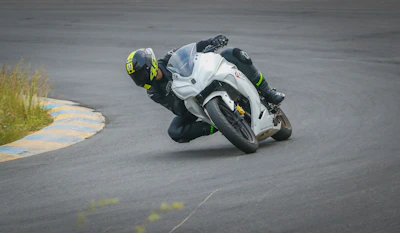 A rider in black and magenta gear leaning into a curve on a closed course, showcasing skill and safety.