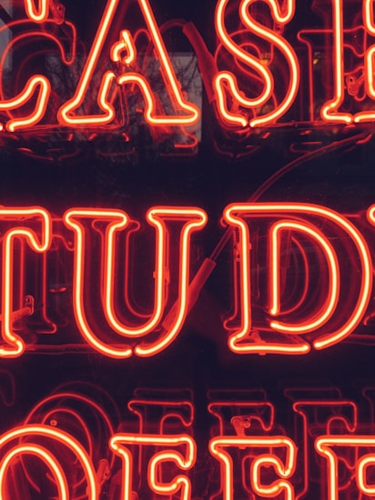 Bright red neon letters forming part of a larger sign that appears to possibly spell out 'CASE STUDY.' The background is dark, making the neon letters stand out prominently.