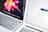 Two laptops are positioned closely side by side. The left laptop displays a vibrant, colorful abstract image, while the right laptop shows a web browser with a search engine page open. The keyboards and part of the screens are visible.
