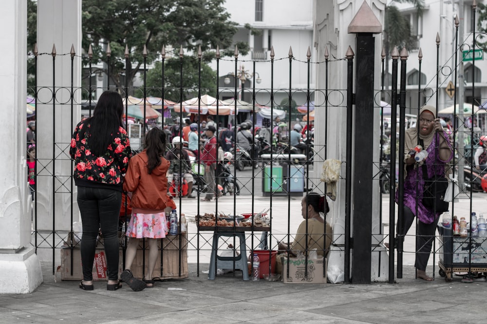 fille portant une veste à fleurs noire debout à côté d’une clôture en acier noir