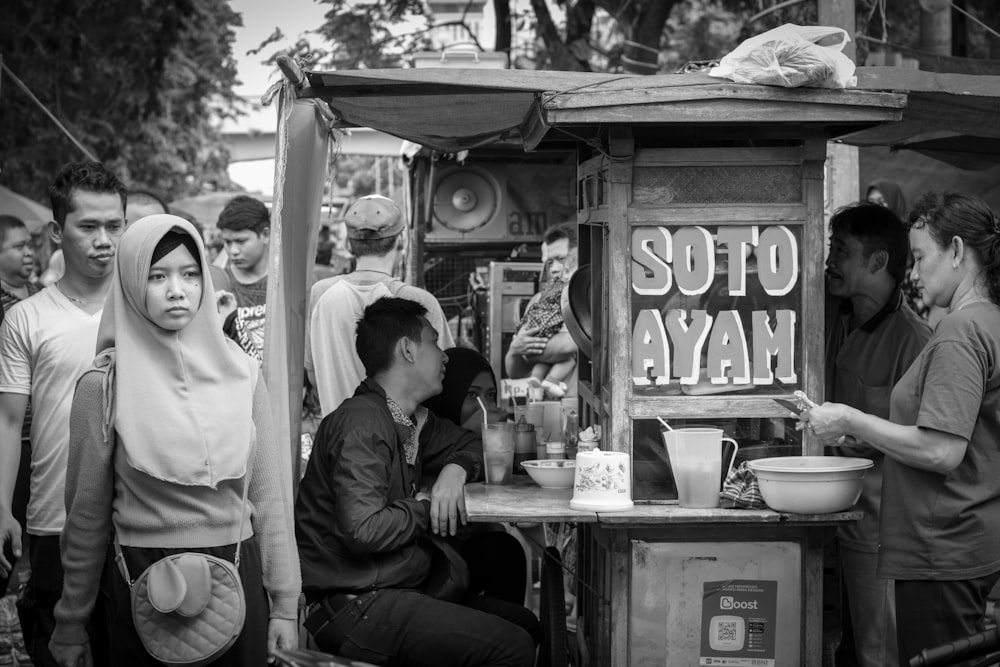 grayscale photography of people standing near booth