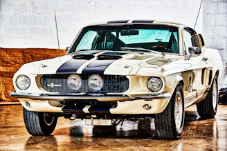 A classic North American muscle car in a softly lit garage with deep brown and charcoal shadows.