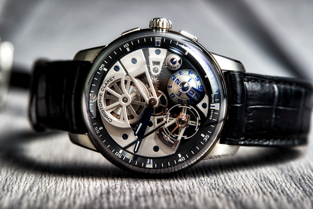 round silver-colored skeleton watch with black leather strap