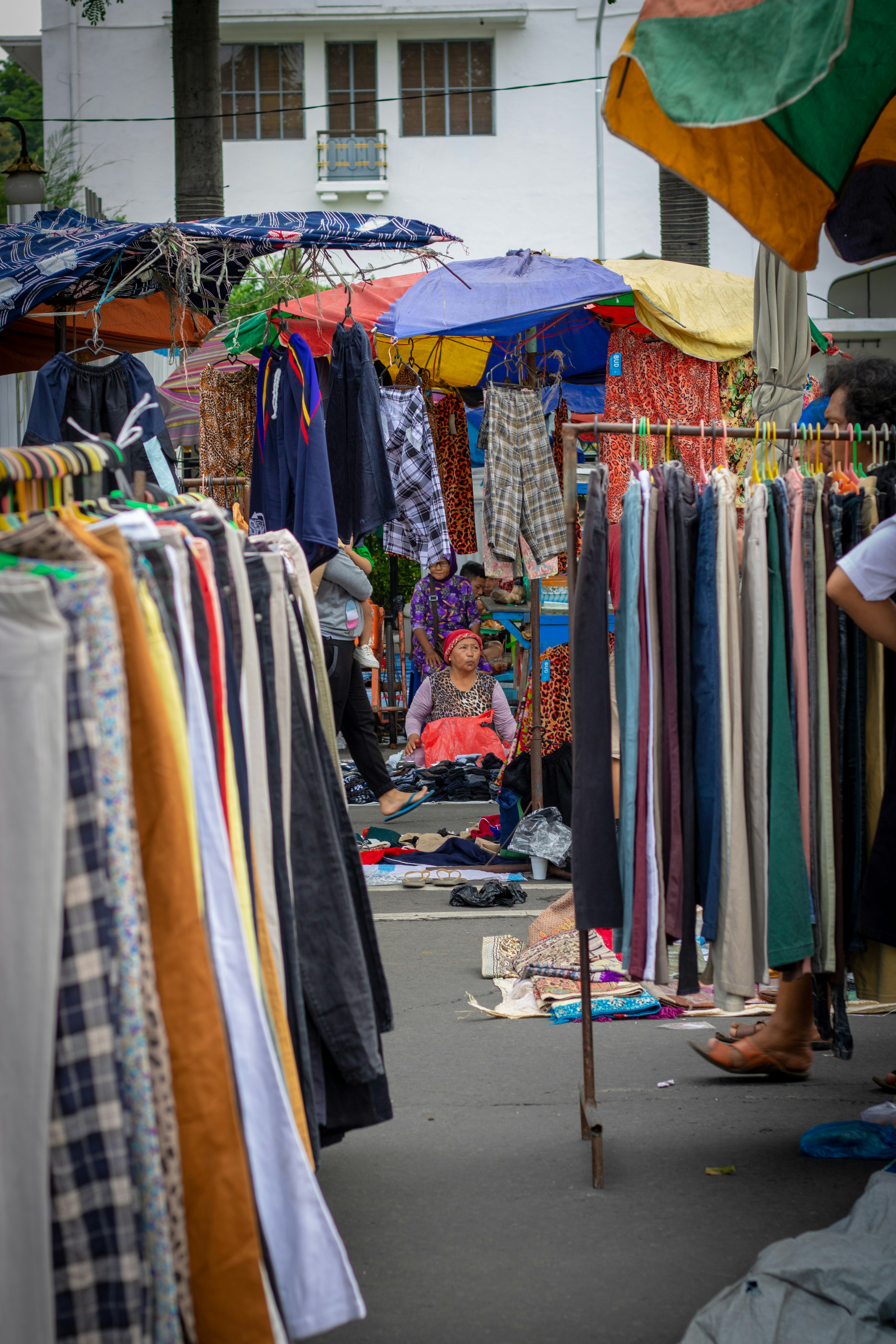 woman sitting while surrounded by clothes