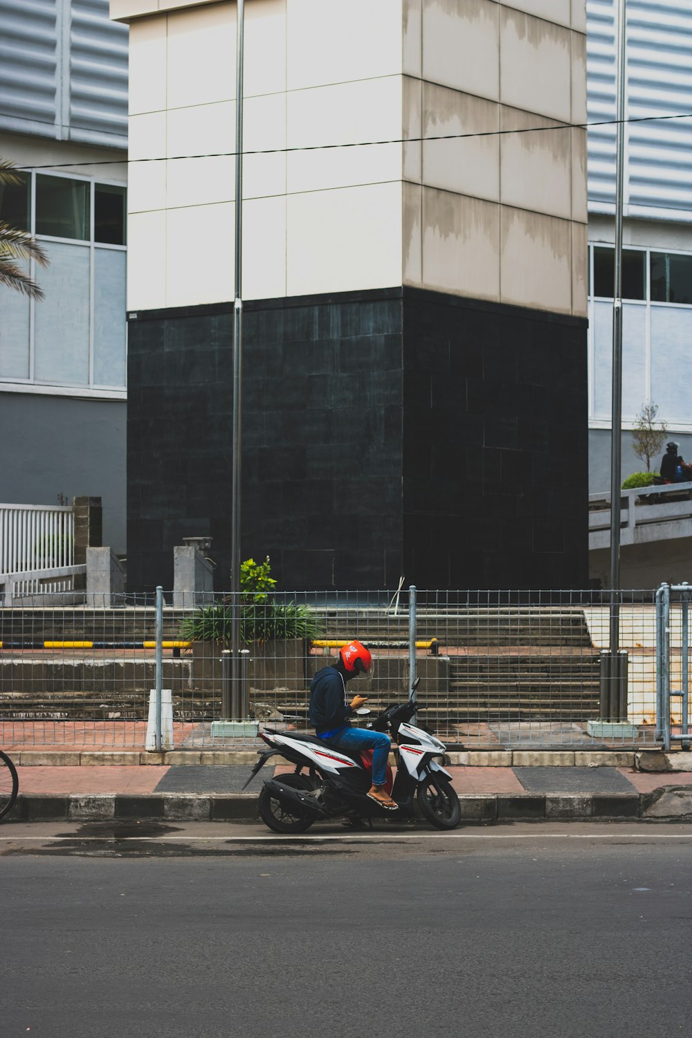 man sitting on motorcycle scooter while holding smartphone