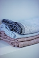 Softly folded antique linen cloth embroidered with intricate patterns beside a cluster of brass buttons.