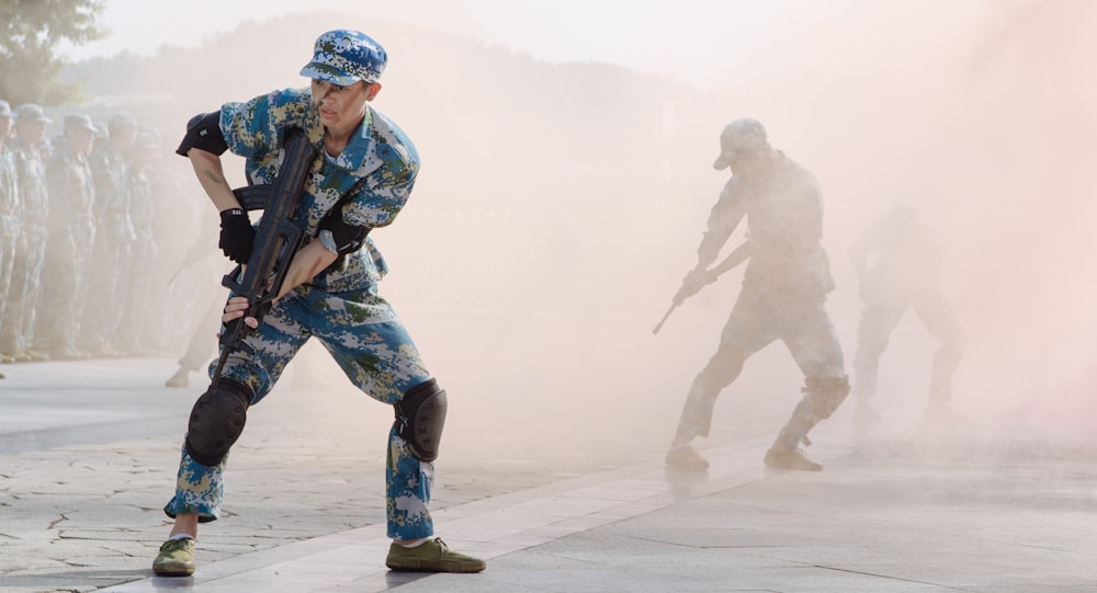 soldier holding black rifle during daytime