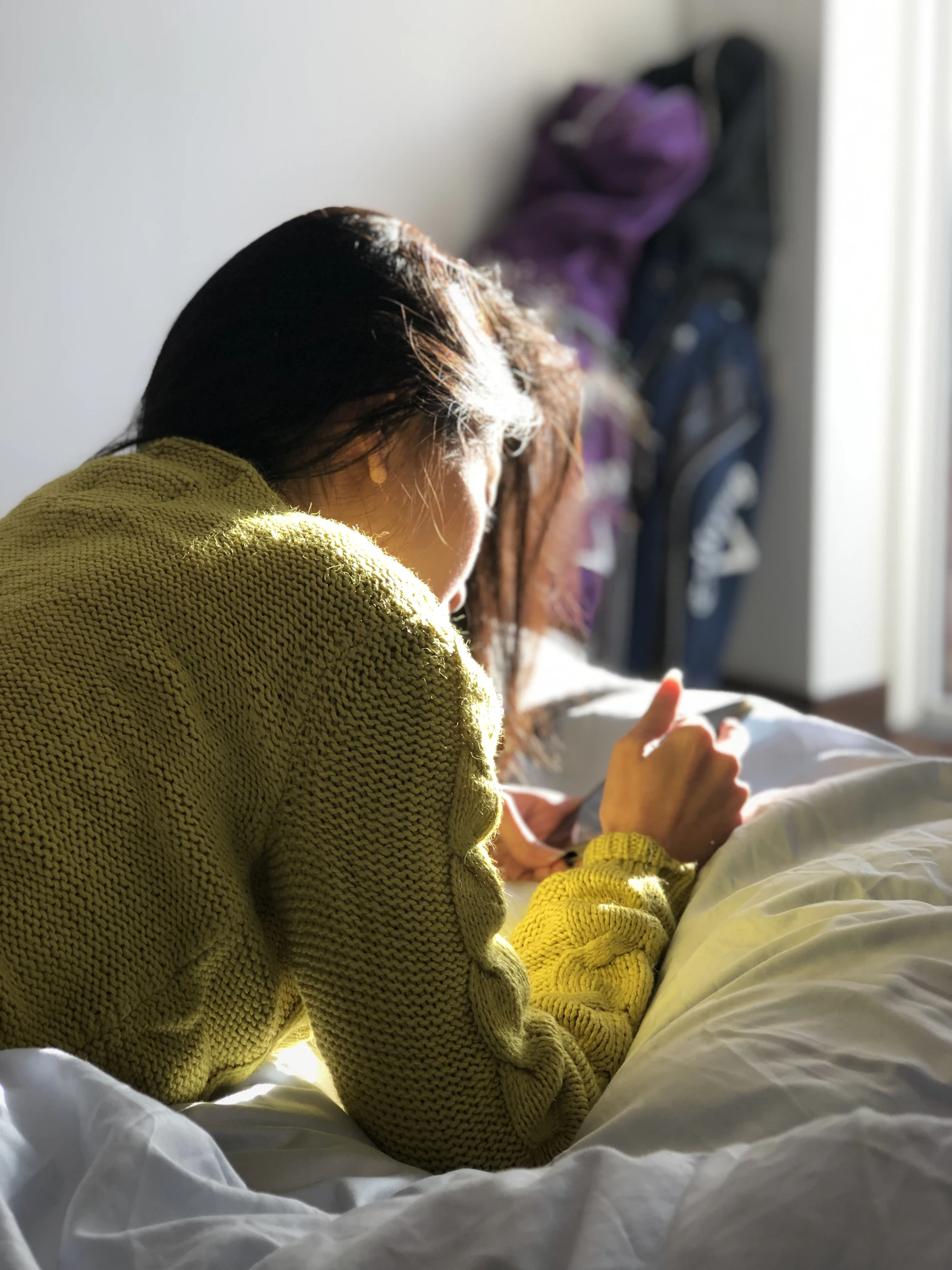 Woman writing in a journal on her bed in warm morning sunlight