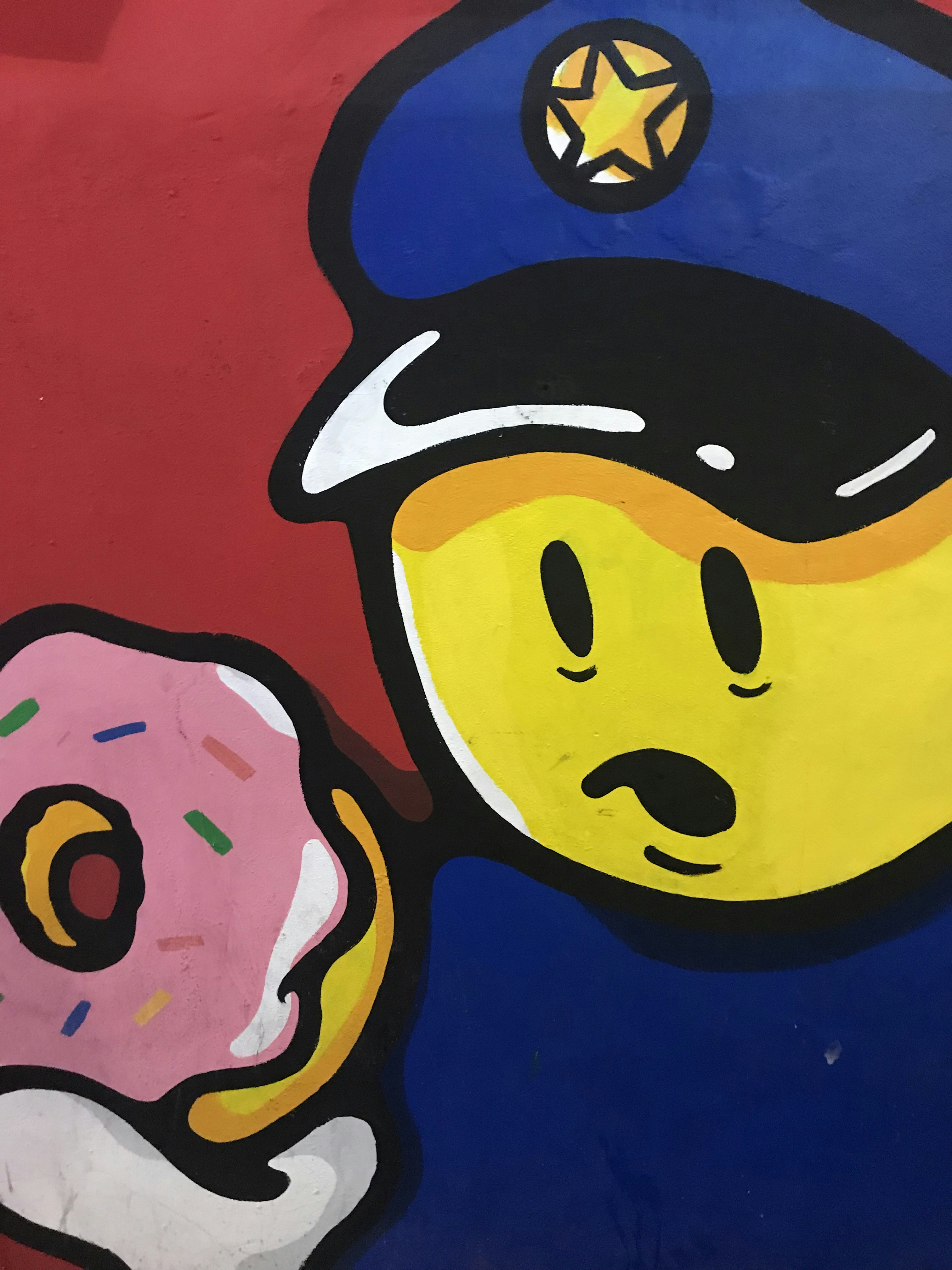 yellow emoji wearing blue police cap holding pink doughnut illustration
