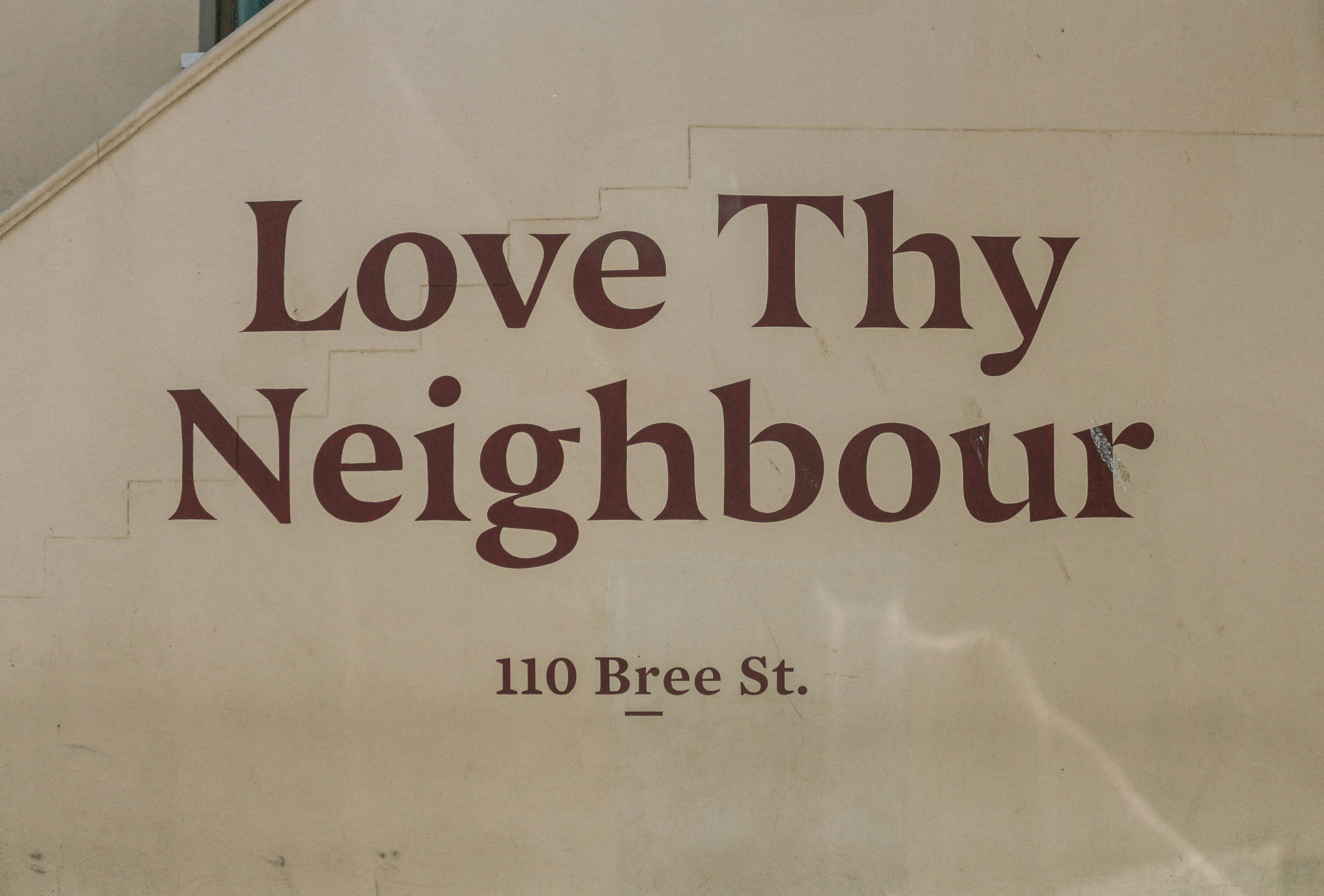 "Love Thy Neighbour 110 Bree St." sign.