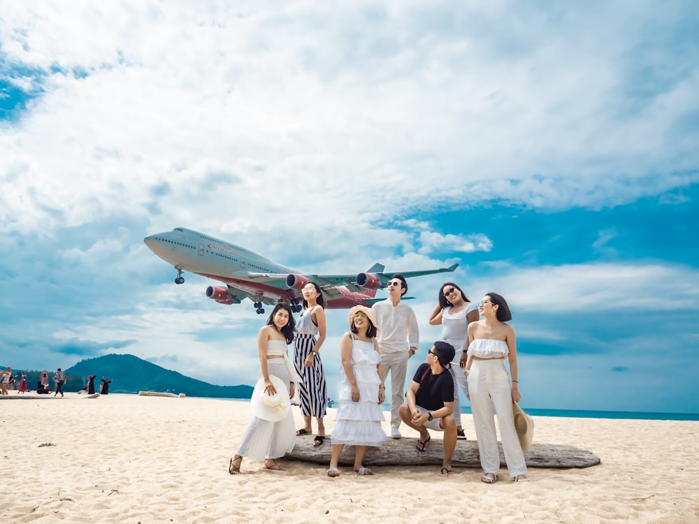 sept personnes debout dans le sable de la plage regardant le ciel