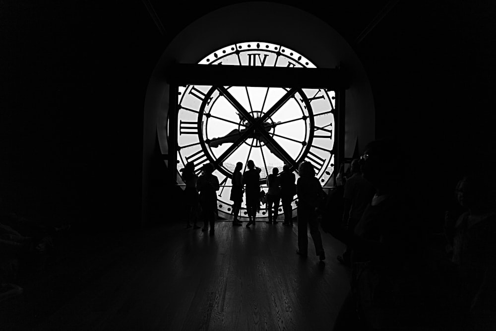 silhouette of people across large clock