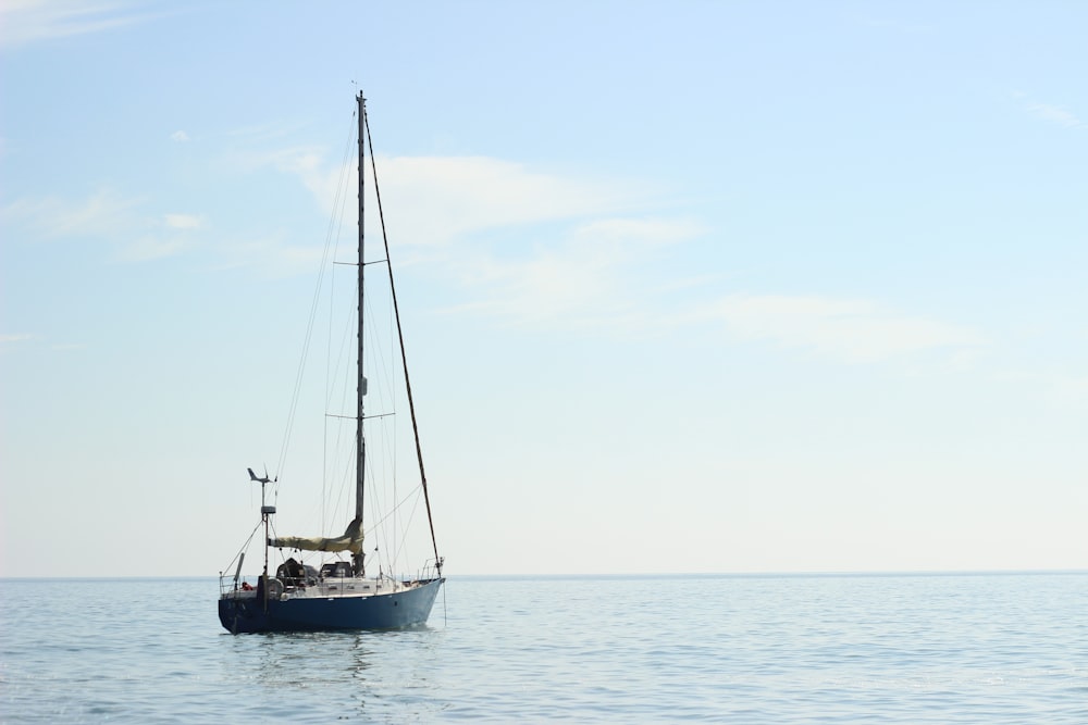 blue and white sail boat on body of water during daytime