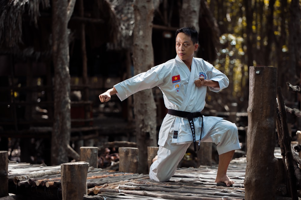 person wearing black belt karate gi training on wooden bridge
