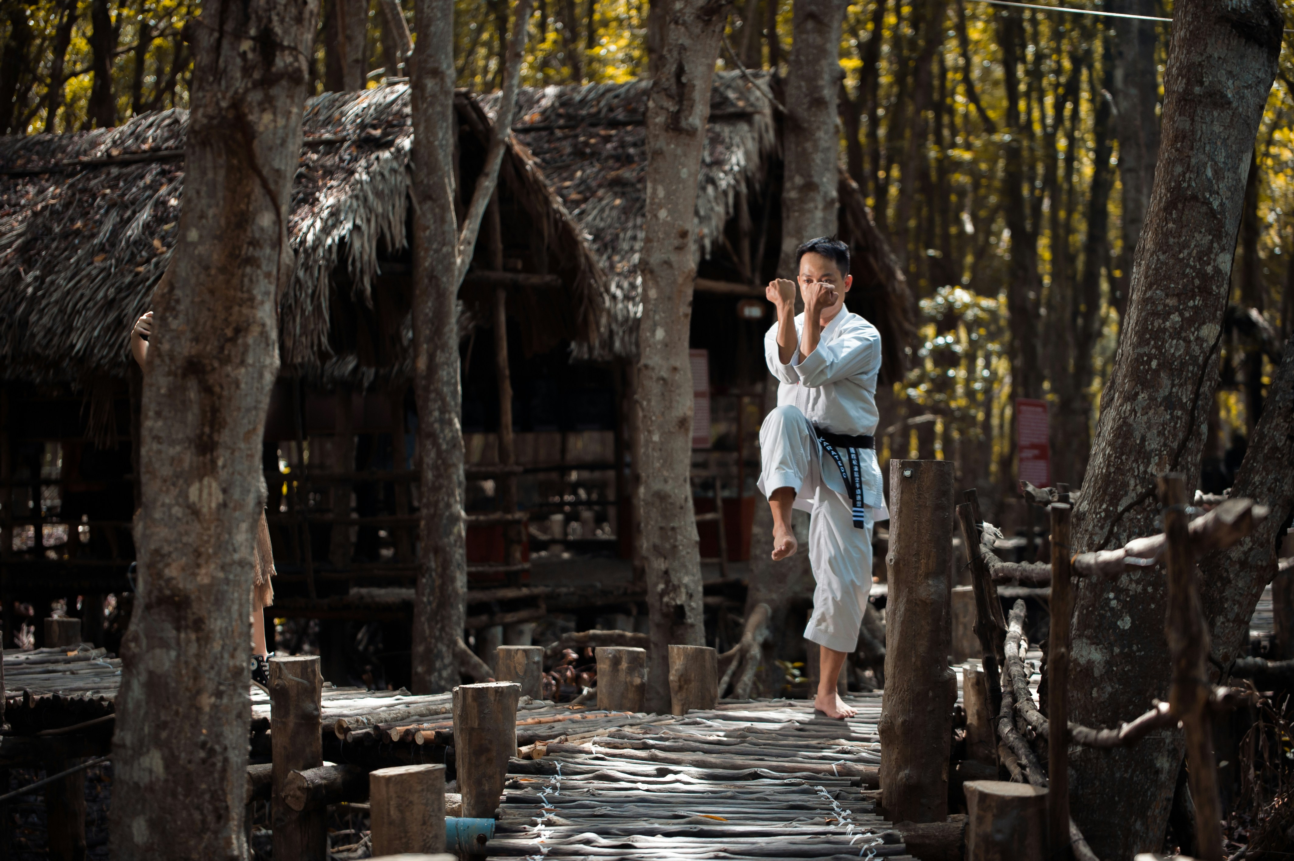 person wearing karate gi across brown hut