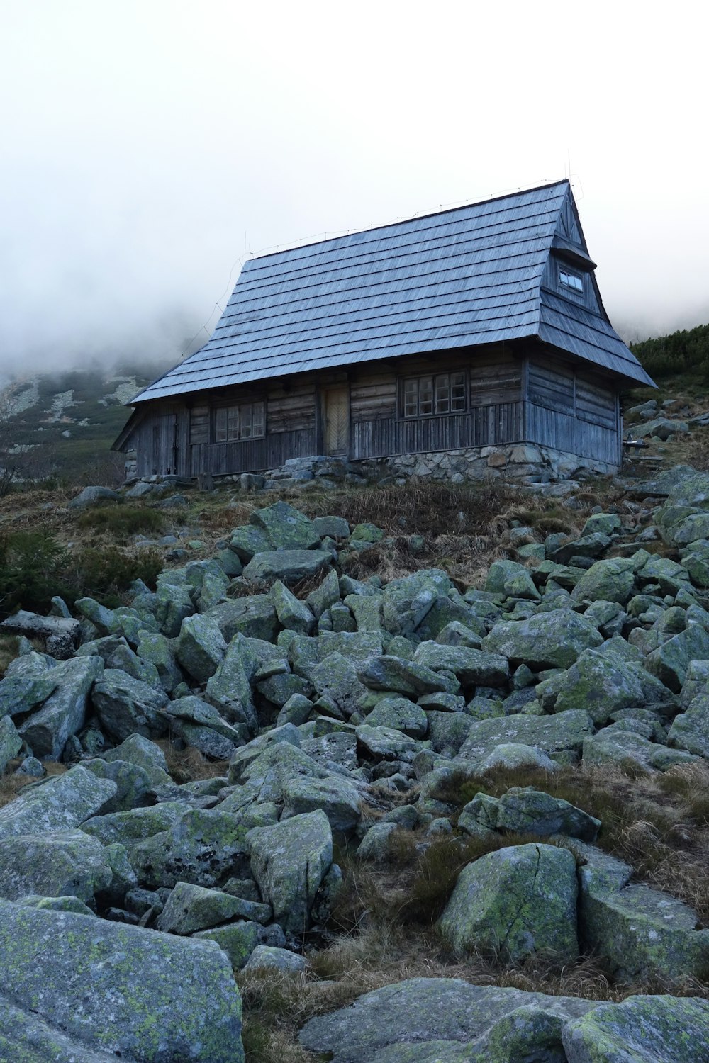 gray wooden house near pile of stones
