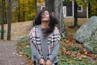 A vibrant scarf blowing gently in the breeze against a backdrop of autumn leaves.