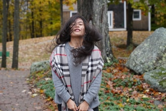 A vibrant scarf blowing gently in the breeze against a backdrop of autumn leaves.