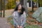 A customer wearing a soft knit scarf while walking through a leafy park on a crisp autumn day.