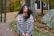 A customer wearing a soft knit scarf while walking through a leafy park on a crisp autumn day.