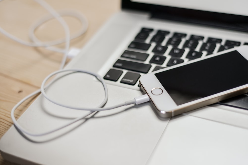 iPhone with cord on top of MacBook