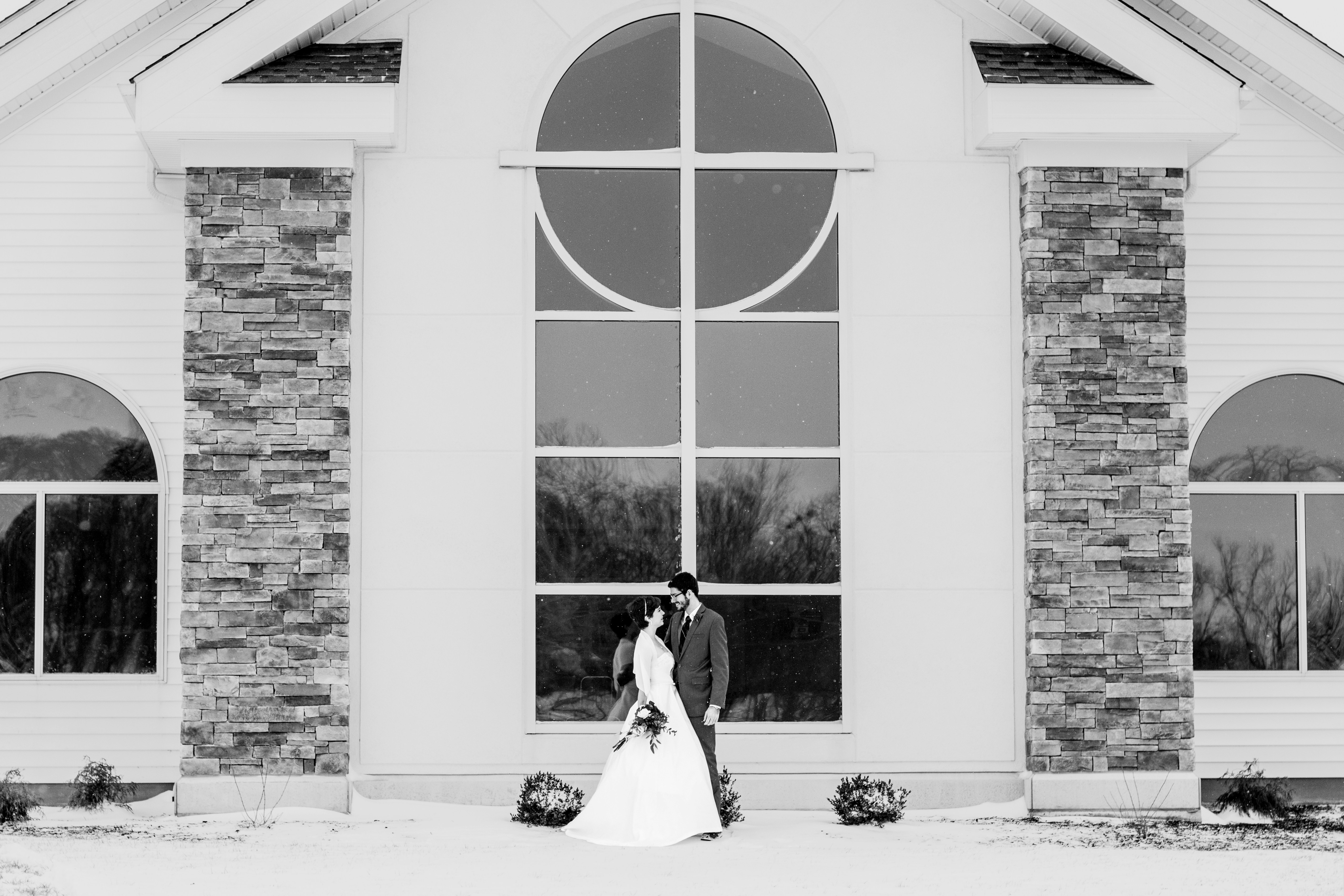 grayscale photo of man and woman standing in front of building