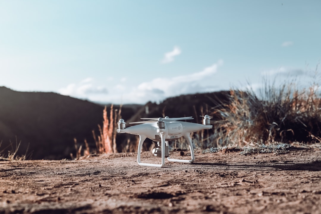 white quadcopter on dirt ground during day