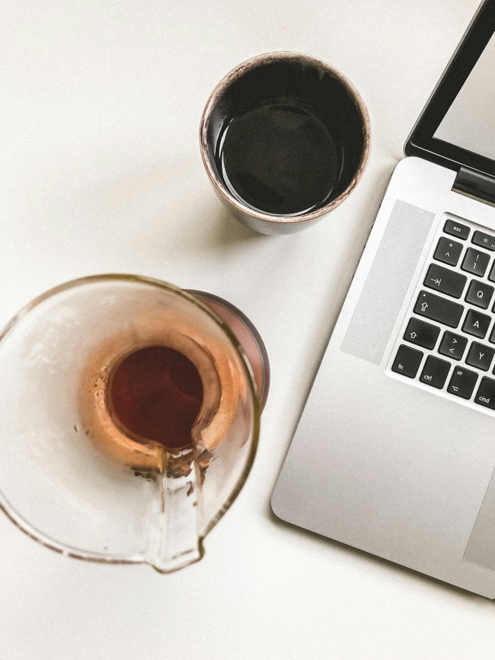 clear glass pitcher and sake cup beside laptop computer