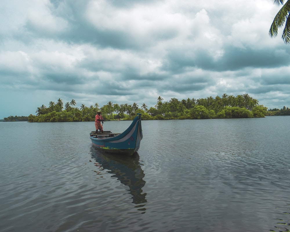 man standing on blue boat during cloudy day